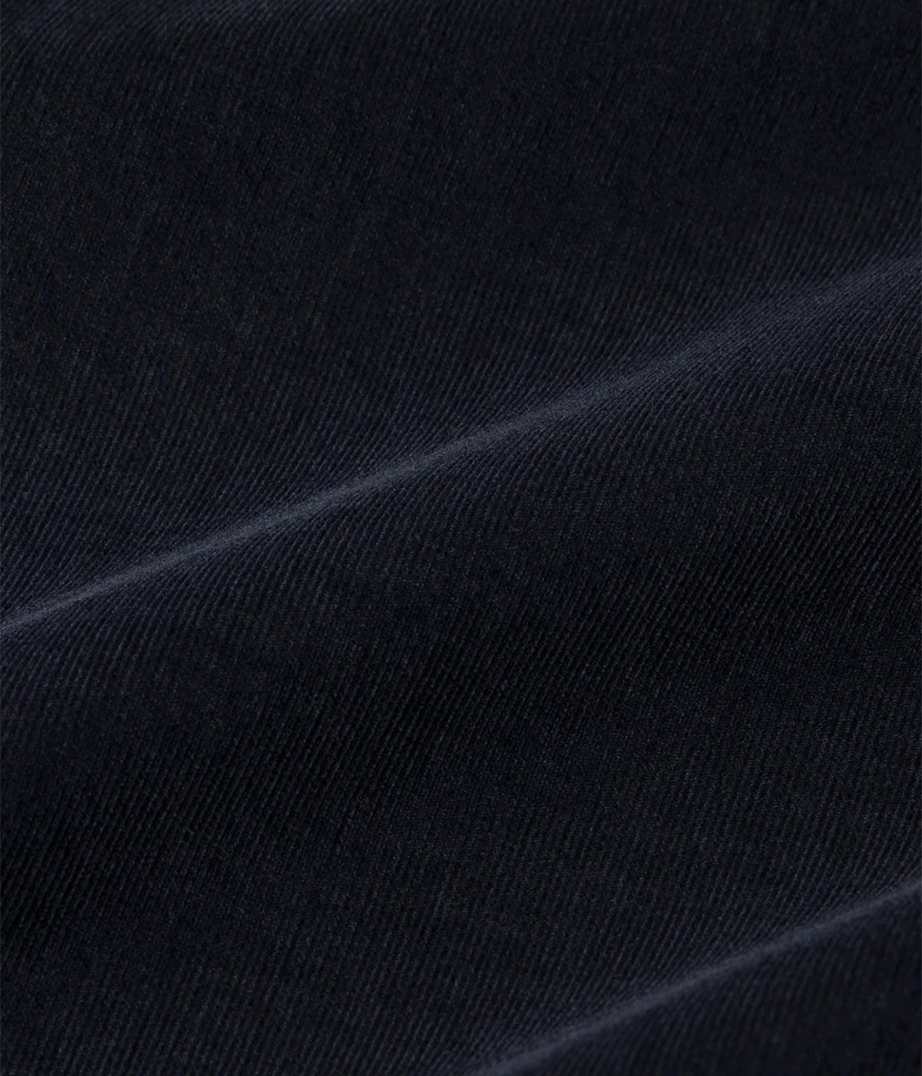 A close-up of dark navy blue fabric with a fine diagonal twill texture and soft folds.