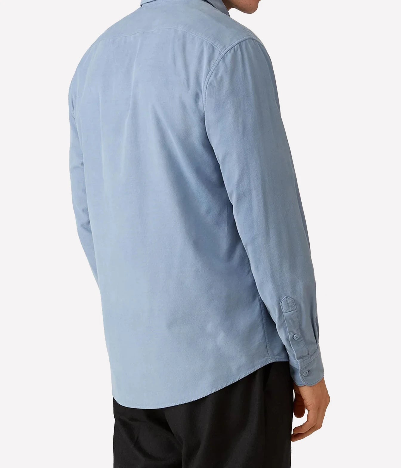 A man wearing a light blue long-sleeve button-up shirt, shown from the back against a plain light gray background.