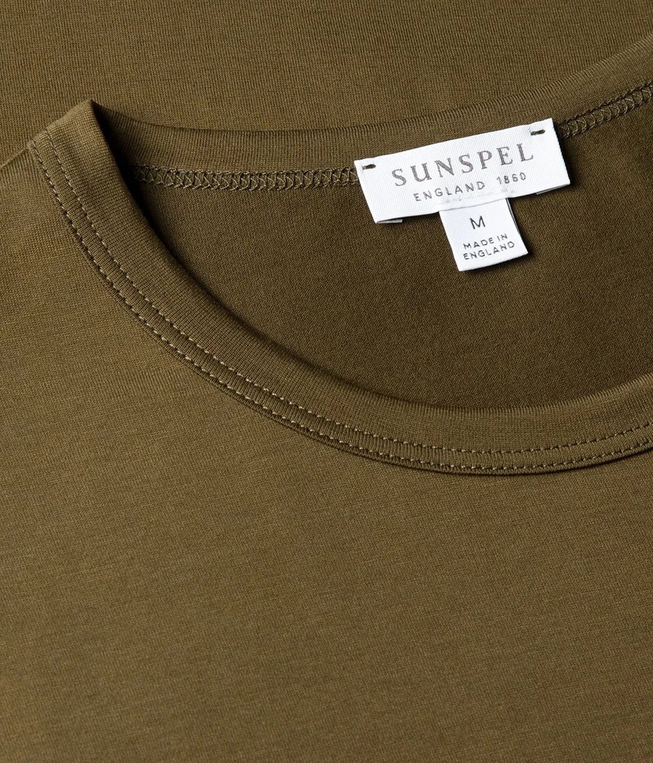Close-up of a crew-neck t-shirt in olive green, showing the inner neck label which reads 'SUNSPEL ENGLAND 1860' and 'MADE IN ENGLAND'.