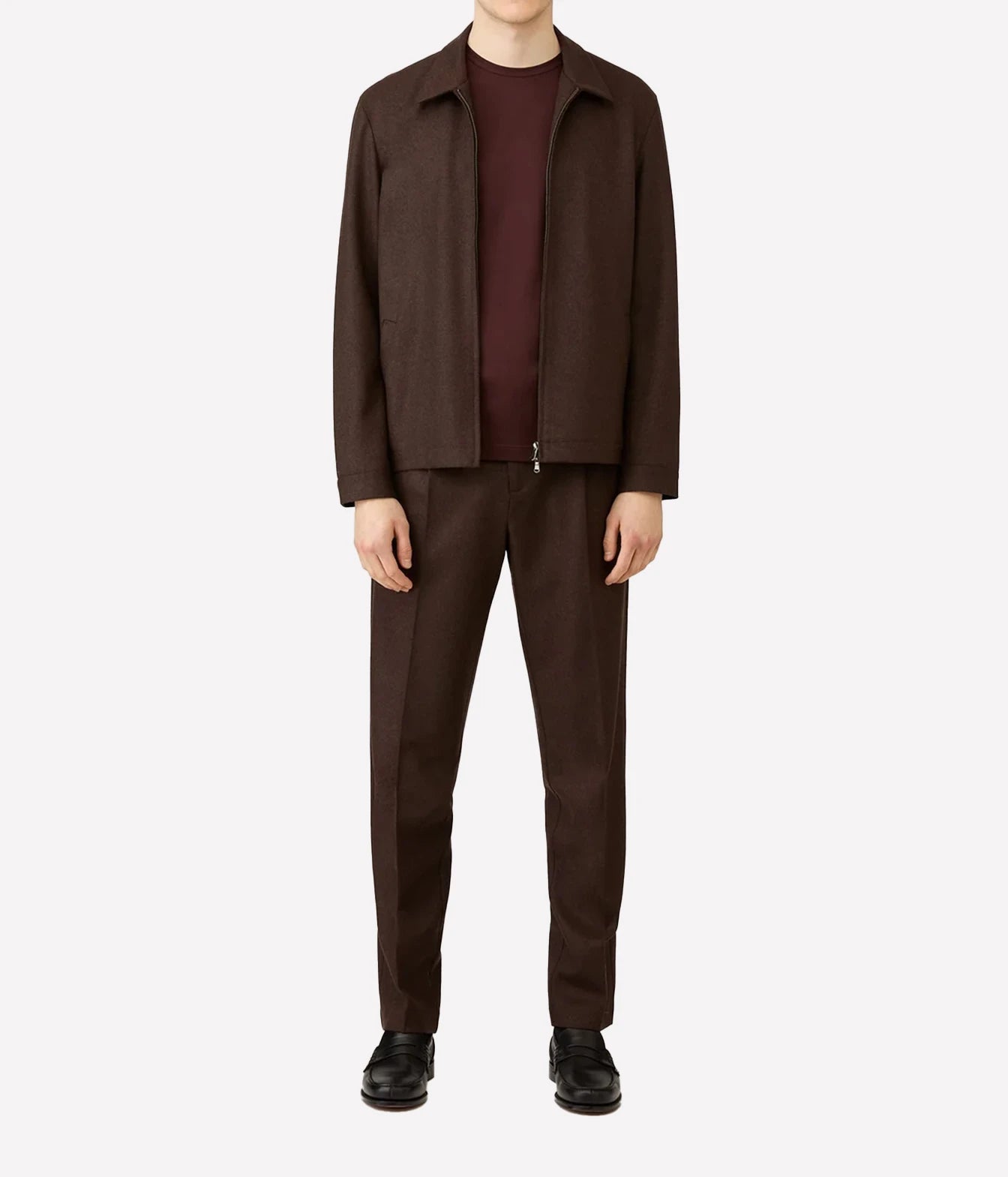 A model wearing a dark brown jacket and matching trousers over a burgundy t-shirt and black shoes, photographed against a solid light gray background.