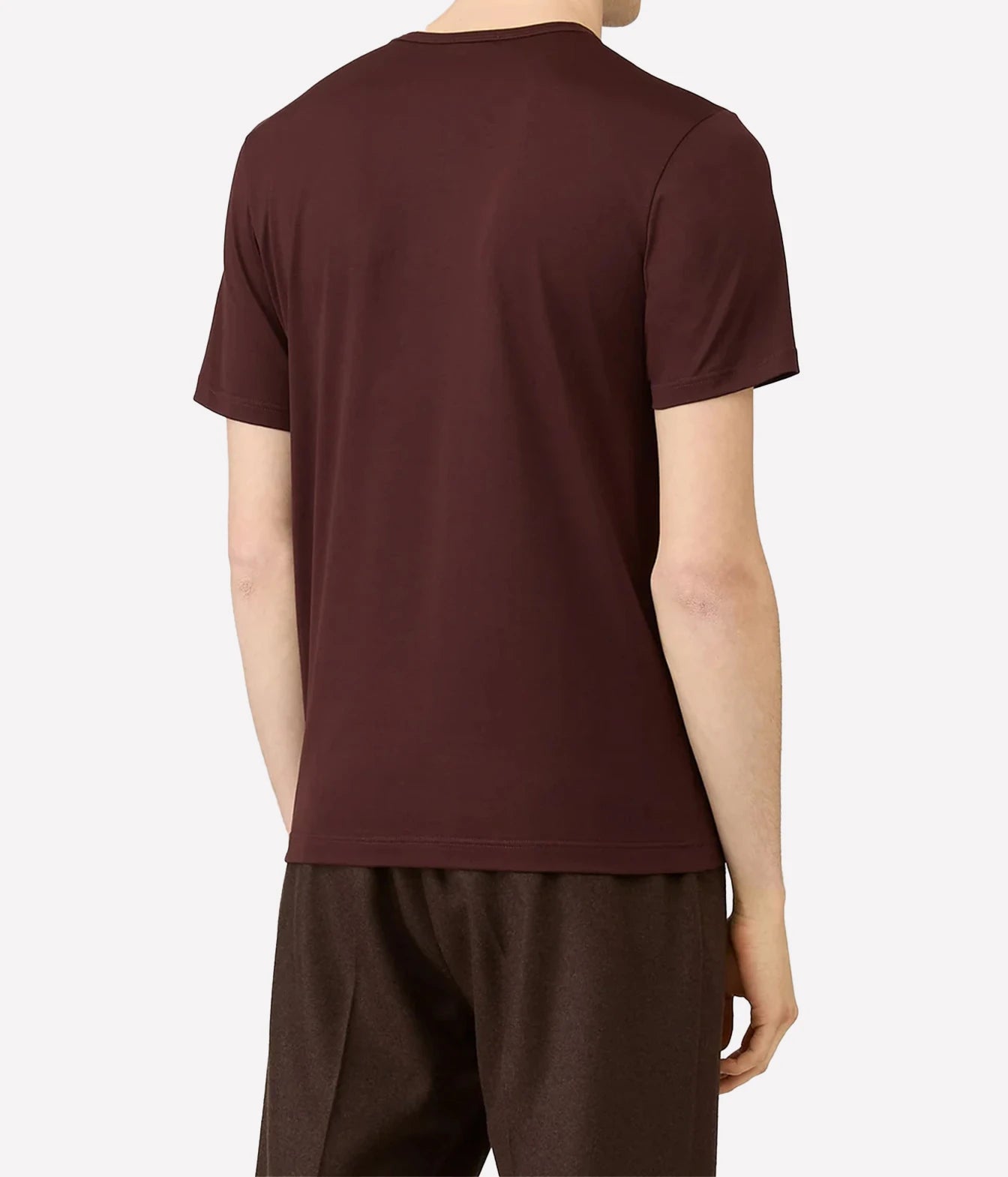 A man viewed from the back wearing a dark burgundy short-sleeve t-shirt and dark brown pants, set against a plain light gray background.