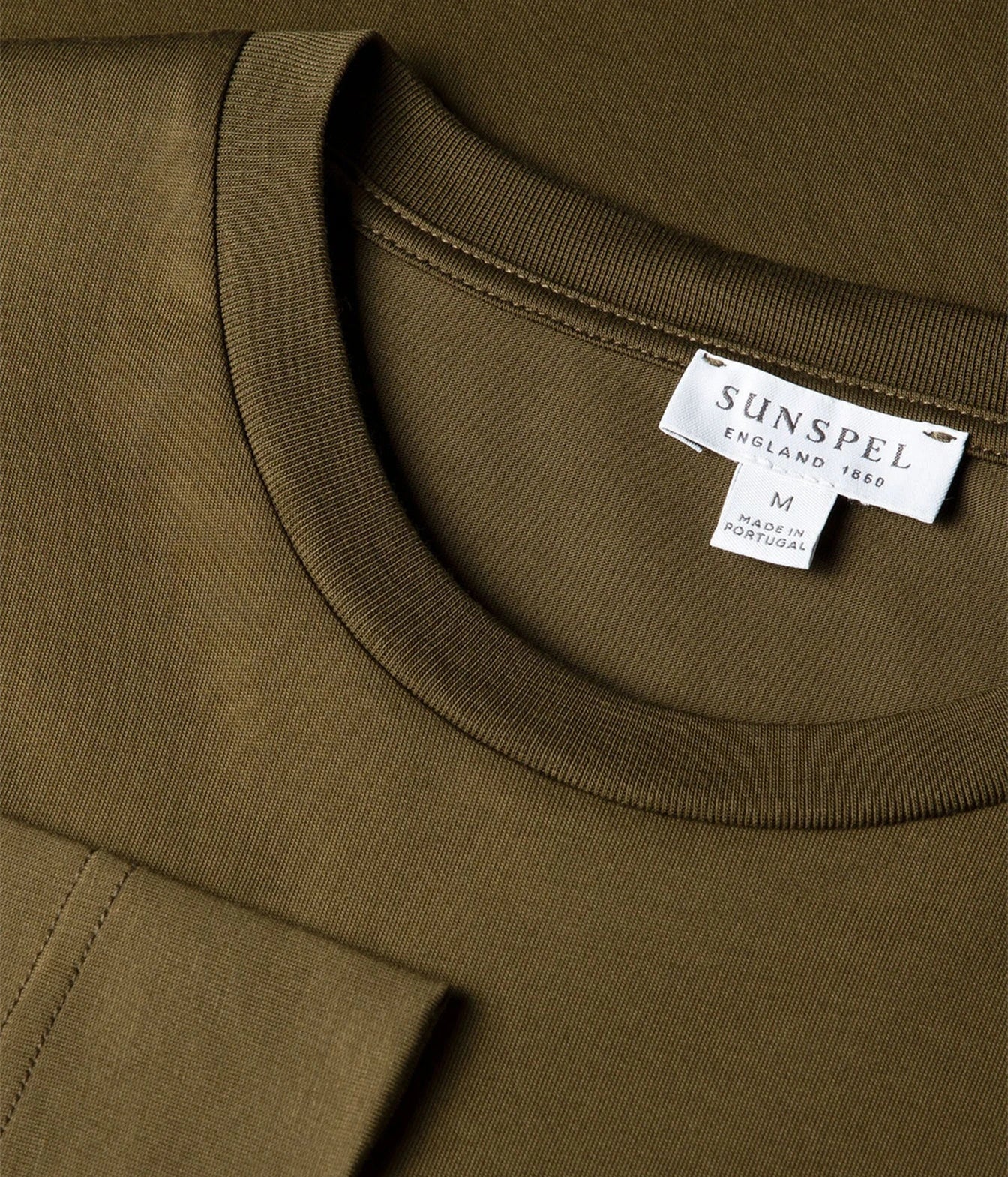 Close-up of a crewneck sweatshirt in olive green, showing the ribbed collar and a white brand label for SUNSPEL.