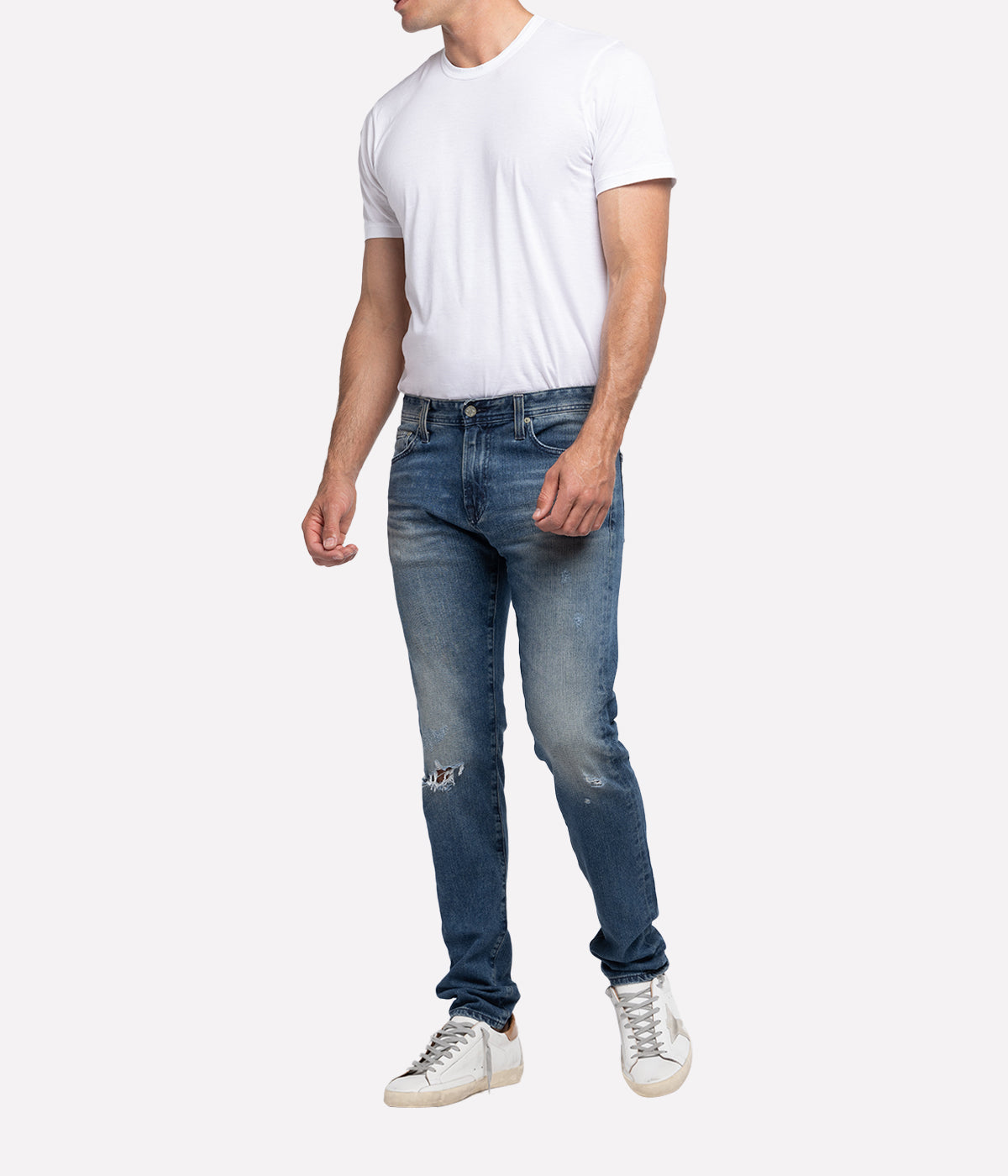 The Dylan Slim Skinny Jeans by AG Jeans in a medium wash with distressed details and knee destruction, featuring a slim fit through the thighs and tapered leg openings.