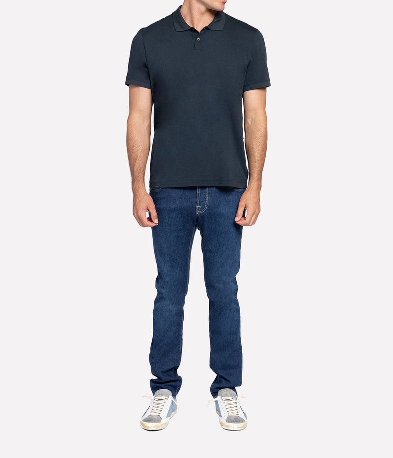 Model wearing the James Perse Luxe Lotus Jersey Polo, showcasing the classic collar, short sleeves, and clean, straight hem. The smooth, elevated jersey fabric drapes effortlessly, offering a polished yet comfortable look perfect for casual or smart styling.